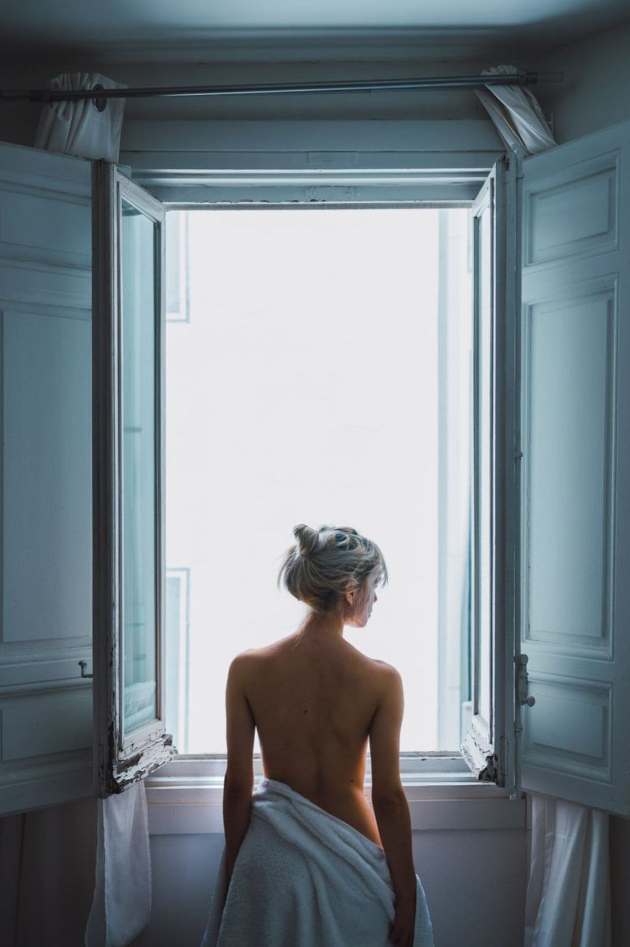 Foto de una mujer de espaldas ante una ventana abierta