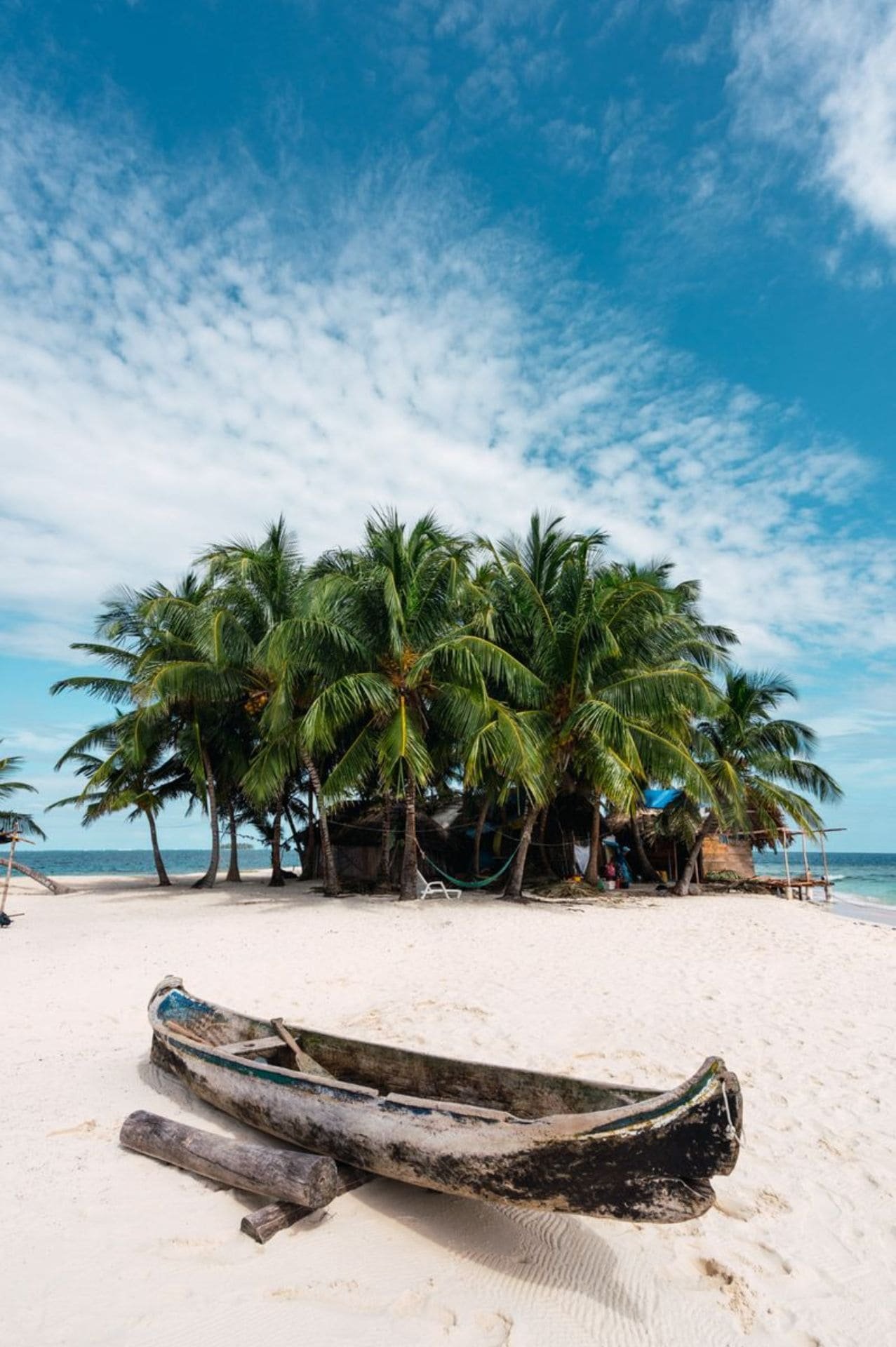 Paisaje de una playa con un árbol en el fondo y en primer plano una canoa