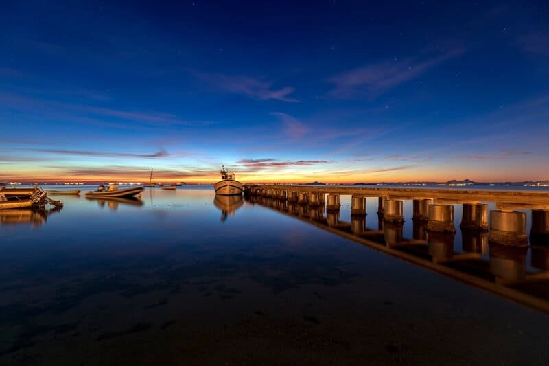 Paisaje lateral de muelle en la noche con el reflejo en el agua